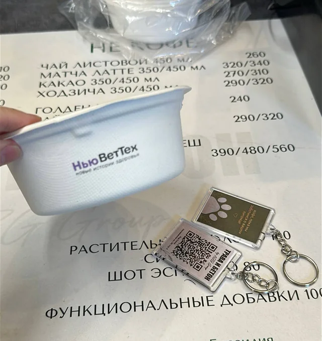 Фирменный стакан Нью Вет Тех и токен рядом с меню кофейни